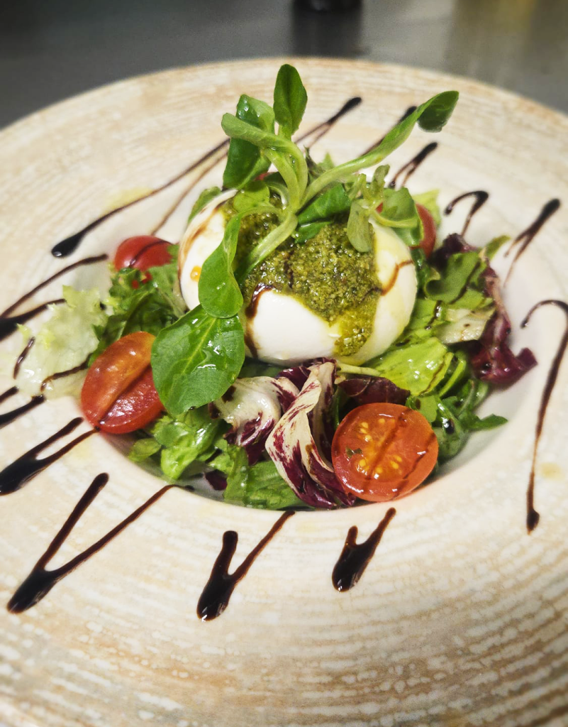 Fresh Burrata Caprese Salad with burrata cheese, cherry tomatoes, arugula and pesto served at Serenada Bistro near Gruž Port in Dubrovnik.